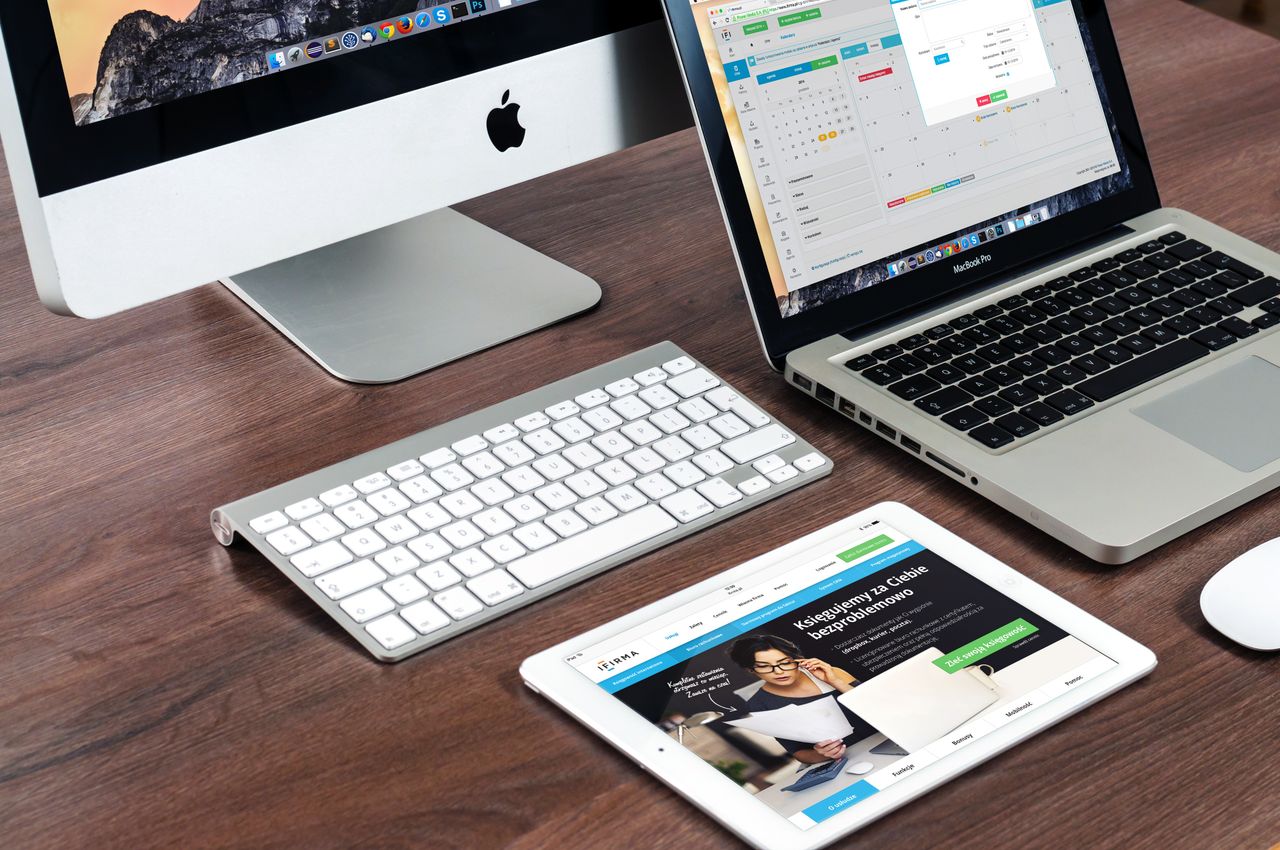 Un bureau de travail élégant mettant en scène des appareils Apple : iMac, MacBook et iPad.